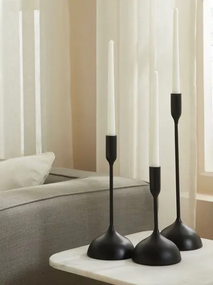 A set of three modern black candle holders on a marble side table. The clean, minimalist styling emphasizes the product's sleek and elegant design.