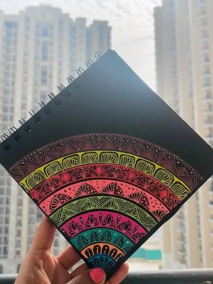 The rainbow semi-circle mandala held up against a city backdrop.
