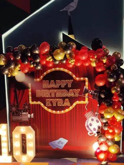 Lights, camera, action for Kyra's 10th birthday. We created a fun movie premiere theme, featuring a red curtain backdrop, a custom birthday marquee, and a balloon arch in classic red, black, and gold, making the birthday girl feel like a star.