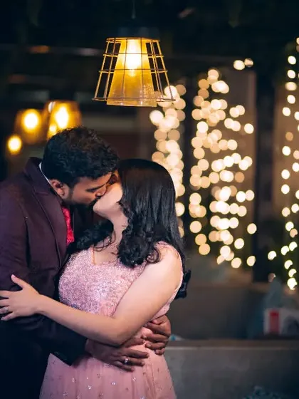 A passionate kiss shared by a couple at their reception, with beautiful bokeh lights creating a magical background.