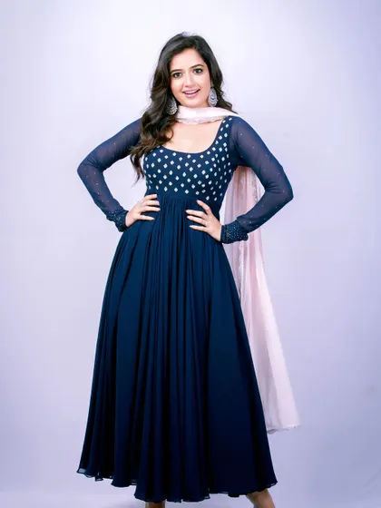 Actress Ashika Ranganath looks radiant in this navy blue Anarkali suit. The bodice features star-like embroidery, and the flowing georgette skirt is paired with a contrasting light pink dupatta for a fresh, modern look.