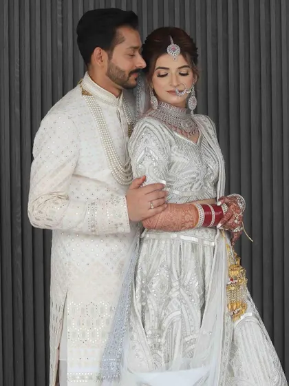 A full-length portrait of the couple. The bride's makeup is designed to look flawless from every angle, enhancing her beauty without overpowering her delicate outfit.