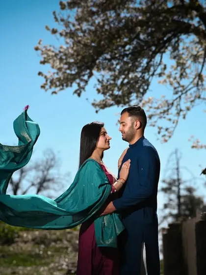 A playful and romantic shot where the bride's dupatta flies in the wind, creating a beautiful, dynamic shape against the clear blue sky. This is a perfect example of capturing movement and emotion.