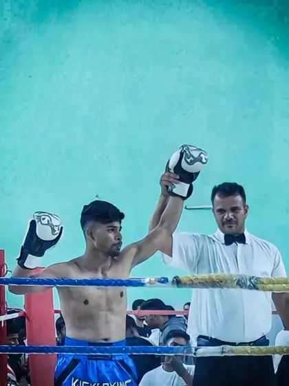 A kickboxer's hand is raised in victory by the referee after a state championship bout. The look of a winner.