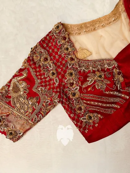 The iconic 'Doli' back on Priya's red raw silk Muhurtham blouse, capturing the essence of Indian heritage in gold zardosi.