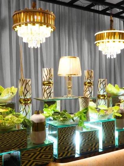 An artfully arranged salad bar under elegant chandeliers. We use multi-level displays and mirrored surfaces to create a sense of depth and luxury, ensuring even the simplest dishes are presented with extraordinary flair.