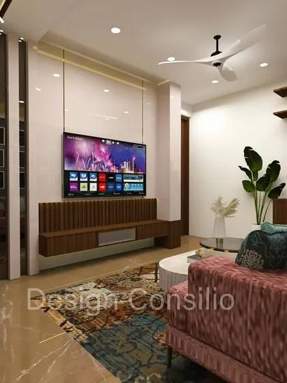 A different angle of the same living room, showing how the design flows. The TV unit is flanked by a large plant, adding a touch of nature to the modern interior.