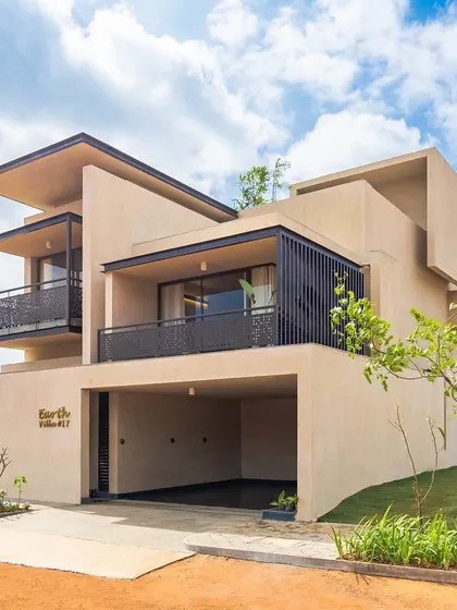 The exterior of an "Earth Villa" at Svamitva Terravana. The design uses a composition of simple, stacked volumes with mud plaster finishing, creating a form that is both modern and deeply connected to the earth.