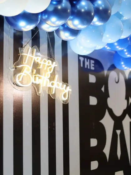 A close-up of the neon 'Happy Birthday' sign against the bold Boss Baby backdrop.
