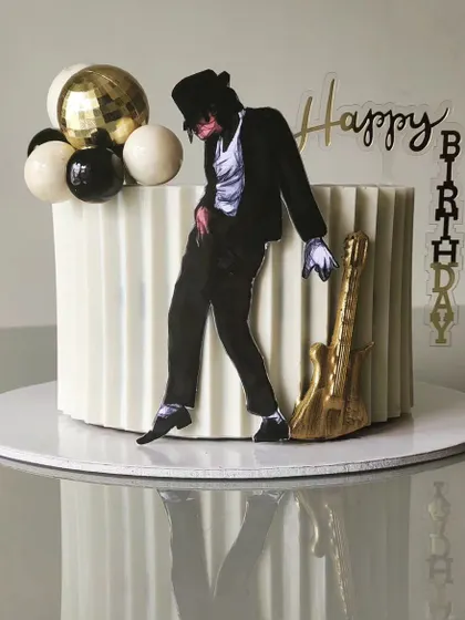 A tribute to the King of Pop, this Michael Jackson-themed cake features his iconic silhouette against a modern white origami-textured buttercream. A golden guitar and disco balls complete the look.