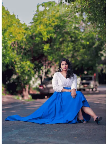 The long train of this navy blue high-low skirt adds a touch of drama to an outdoor photoshoot, creating a beautiful contrast with the white floral crop top.