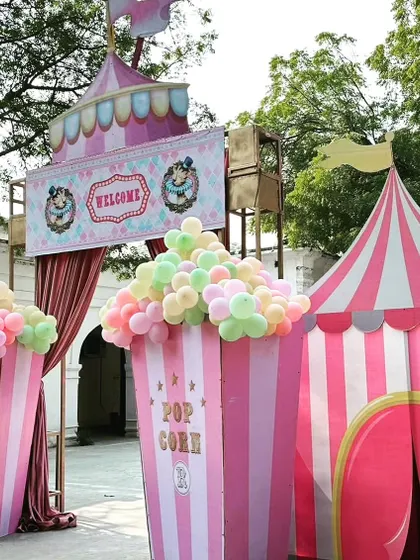 The grand entrance to the carnival party, featuring giant popcorn box props and a classic red-and-white striped circus tent.