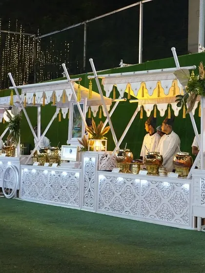An elegant, all-white buffet setup designed to look like royal food carts. The intricate latticework and clean lines create a sophisticated and regal atmosphere for any upscale wedding or social gathering.
