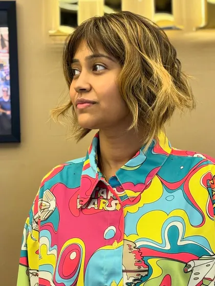 A bold and artistic look, combining a short, choppy bob with blonde highlights and trendy bangs.