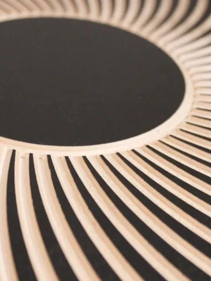 A close-up on the carved lines spiraling towards the black center, showcasing the texture and precision of the woodwork.