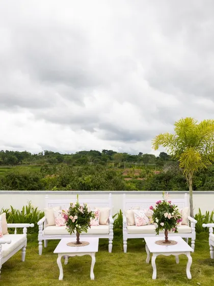 A tranquil seating area at a farmhouse event, with white wooden benches overlooking a beautiful green landscape. Perfect for guests to relax and take in the view.