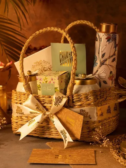 This lovely Diwali gift basket, made from woven Kauna grass, is not only beautiful but also reusable. It's filled with curated treats and a printed copper bottle.