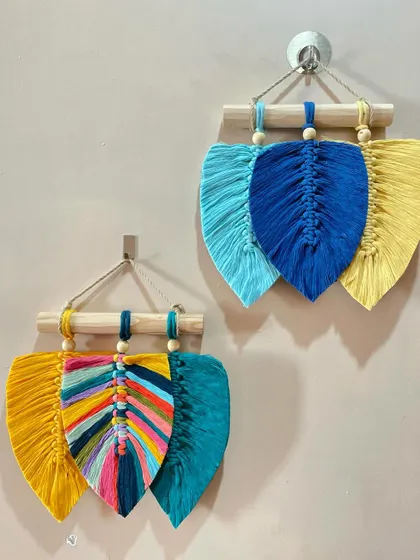 A pair of mini leaf wall hangings. One features a multi-colored rainbow leaf, while the other uses a simple, three-color design.