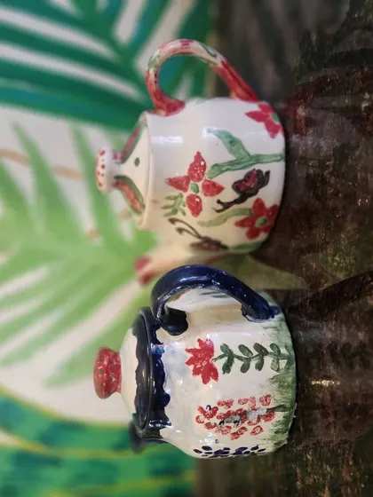 Another view of the charming, hand painted ceramic watering cans, perfect as a small decorative item or a unique gift.