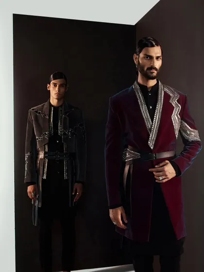 Another powerful shot of the grey and wine-colored velvet jackets. The contrast of the dark background emphasizes the rich colors and metallic details, creating a sense of grandeur.