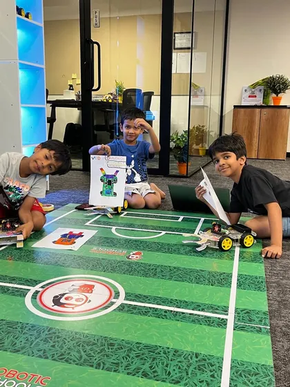 Our students are in full preparation mode for a robot soccer competition. They are seen here with their custom-designed robots on the game mat, strategizing and making final adjustments.