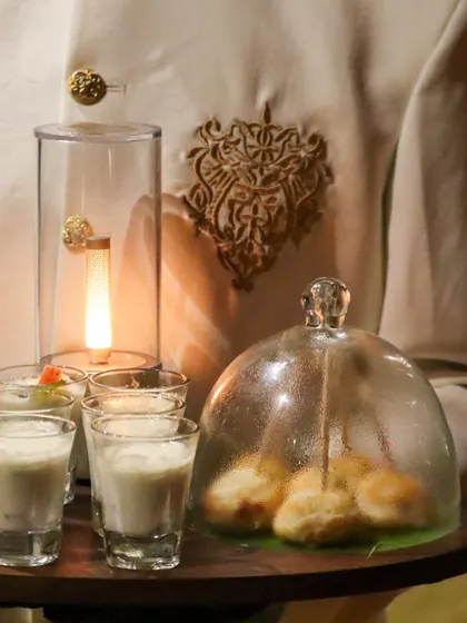A server presents an array of our signature small bites, including delicate steamed buns under a glass cloche. This theatrical presentation adds a touch of drama and sophistication to the service.