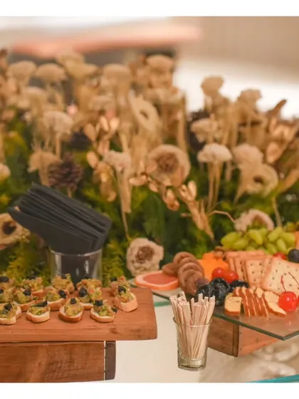 An artfully arranged section of a grazing table, combining gourmet bites with rustic floral decor to create a beautiful and inviting food station.