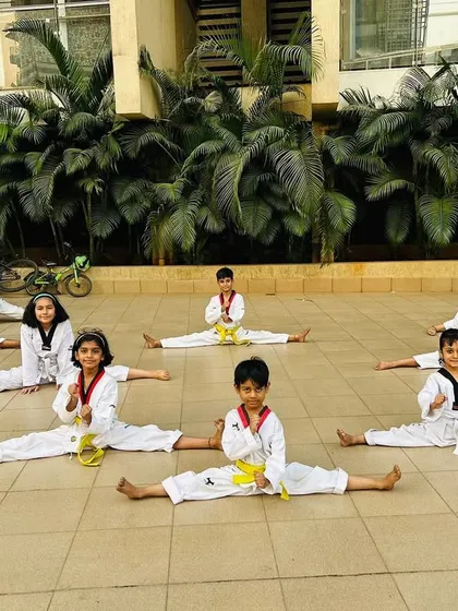 Another group of students demonstrating their middle splits during an outdoor training session.