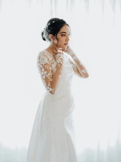 An elegant, high-key portrait of the bride. The bright, airy background and the delicate details of her dress create a timeless and ethereal image.