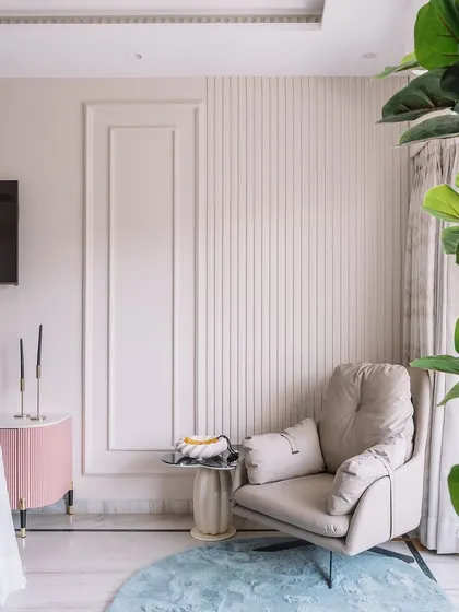 A cozy reading corner in the 'Modern Muse' bedroom after its transformation. The space features a comfortable armchair, elegant wall paneling, and a touch of greenery, creating a perfect spot to unwind.