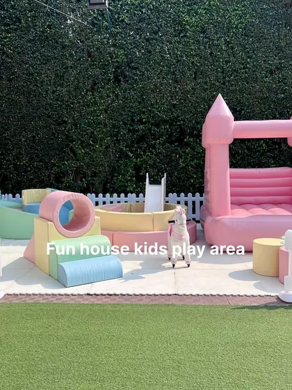 This outdoor setup combines a pink bouncy castle with a smaller pastel soft play area, perfect for parties with a wide age range of kids.