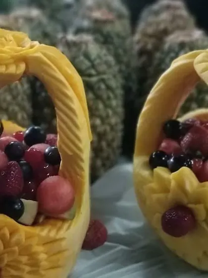 A pair of beautifully carved pumpkin baskets filled with fresh fruit, with whole pineapples in the background. This shows how I can create a stunning and cohesive dessert or fruit station.