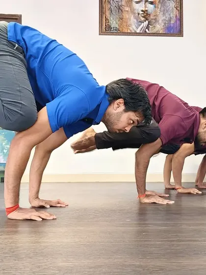 A group of students practicing an arm balance together, motivating each other to find their strength.