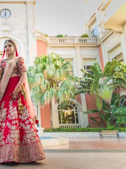 A duplicate of ID 92, a magnificent portrait of the bride in her stunning red lehenga, set against the grand architecture of a palace-like venue.