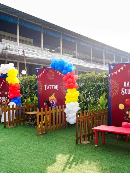 A wide view of the creative stations at a circus-themed party, including a tattoo booth and a balloon sculptor.