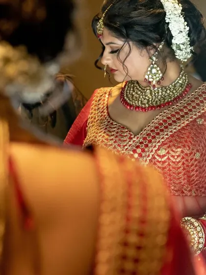 A close-up of the bride's getting-ready process, with a focus on her intricate jewelry and the beautiful floral arrangement in her hair.