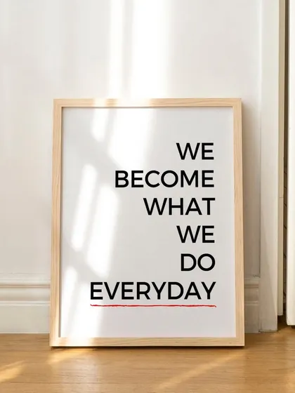 This image showcases the "We Become What We Do Everyday" print in a simple wood frame, leaning against a wall for a casual, modern look. It's a versatile piece for any contemporary home.