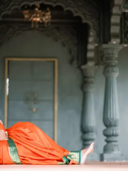 A full-length shot of the mother-to-be seated, looking down at her baby bump. This pose is both classic and deeply emotional, set against a beautiful architectural backdrop.