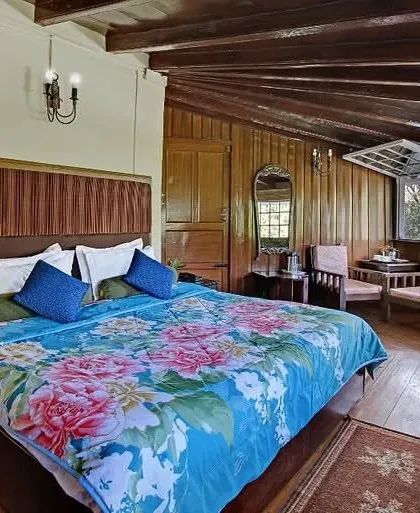 A rustic-chic guest room with exposed wooden ceiling beams and wood-paneled walls, offering a cozy, cabin-like experience.