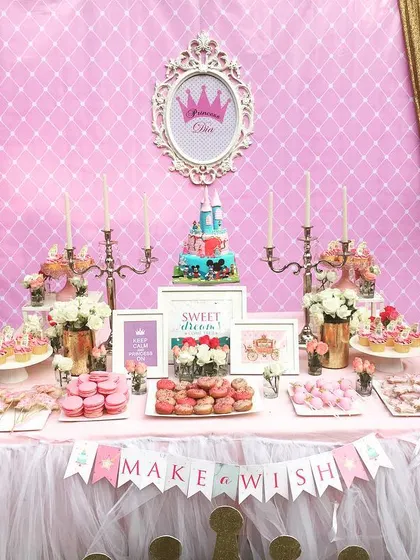 A royal dessert table for a princess birthday. The setup featured castle turrets, a royal crown emblem, and a "Make a Wish" banner for a fairytale celebration.