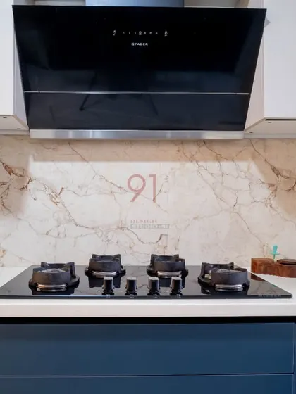 The hob and chimney are set against a marble-finish backsplash, adding a touch of luxury to the minimalist design.