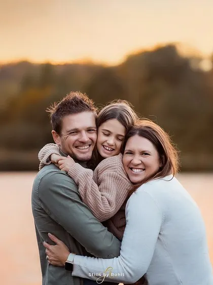 A beautiful, tight family hug against the warm glow of a sunset over the water. These are the simple, authentic moments of connection that I strive to capture in every family photography session.