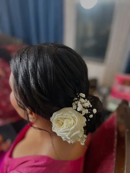 A side view of the classic floral bun, showing how the white rose is neatly tucked into the side. This style is perfect for pairing with a silk saree.