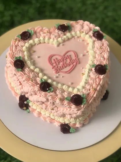 A heart-shaped vintage cake with pink and burgundy buttercream details.