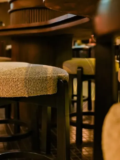 A close-up of the boucle-upholstered bar stools we created for 'Call Me Ten'. The texture of the fabric was chosen to add a layer of warmth and tactile comfort to the moody, atmospheric interior.