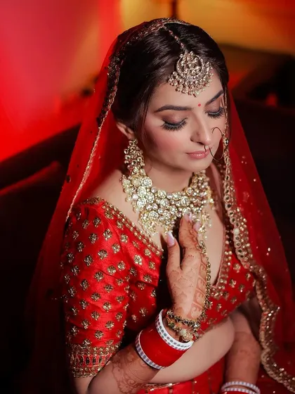 A close-up of a bride in her red wedding outfit, highlighting her kundan jewelry.