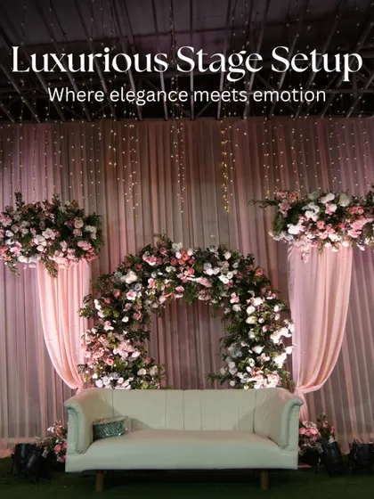 A luxurious stage setup for a reception, where elegance meets emotion. This design features a beautiful floral arch, soft pink draping, and dramatic lighting, creating the perfect focal point for the happy couple.