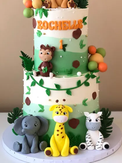 A close-up of a two-tiered safari cake, showing the adorable fondant animals like the elephant, giraffe, and zebra.