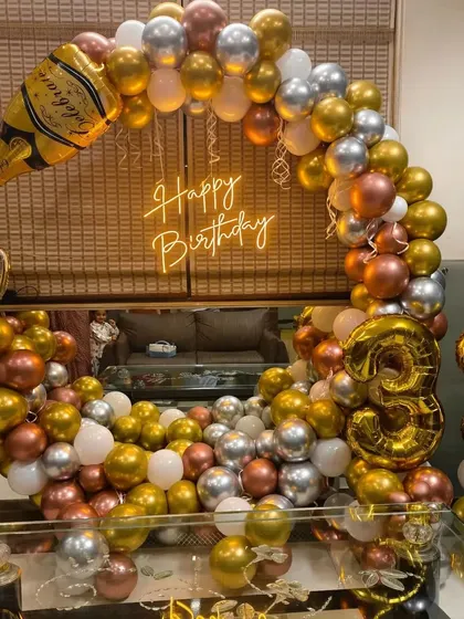 A 33rd birthday party with a champagne and beer theme, using gold, silver, and copper balloons.