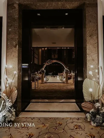 A classic and elegant reception setup symbolizing everlasting love. The stage features a modern, minimalist backdrop with custom monograms, floral arrangements, and soft lighting.